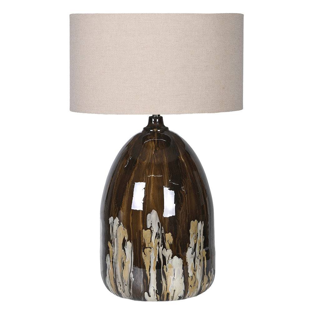 Large glazed ceramic table lamp in brown and cream tones with a neutral fabric drum shade, shown against a plain background.