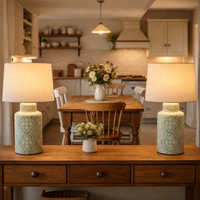 pair of green and white ceramic lamps, lighting a wooden console in a kitchen/diner interior.