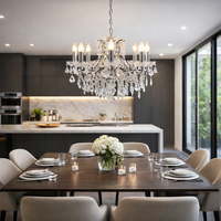 Dining room with a crystal chandelier, table set for dinner, and kitchen in the background.