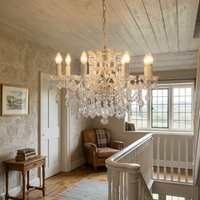 8 branch chandelier on a landing in a stairwell, with leather chair, small side tables and window view.