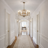 Pair of six branch crystal chandeliers in a long country house hallway. 