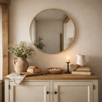 Circular 71 cm  mirror in a cottage setting over a wooden sideboard against a pale plastered wall. 