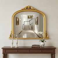 Smaller ornate gold overmantle mirror with arched top and decorative scrollwork crest.