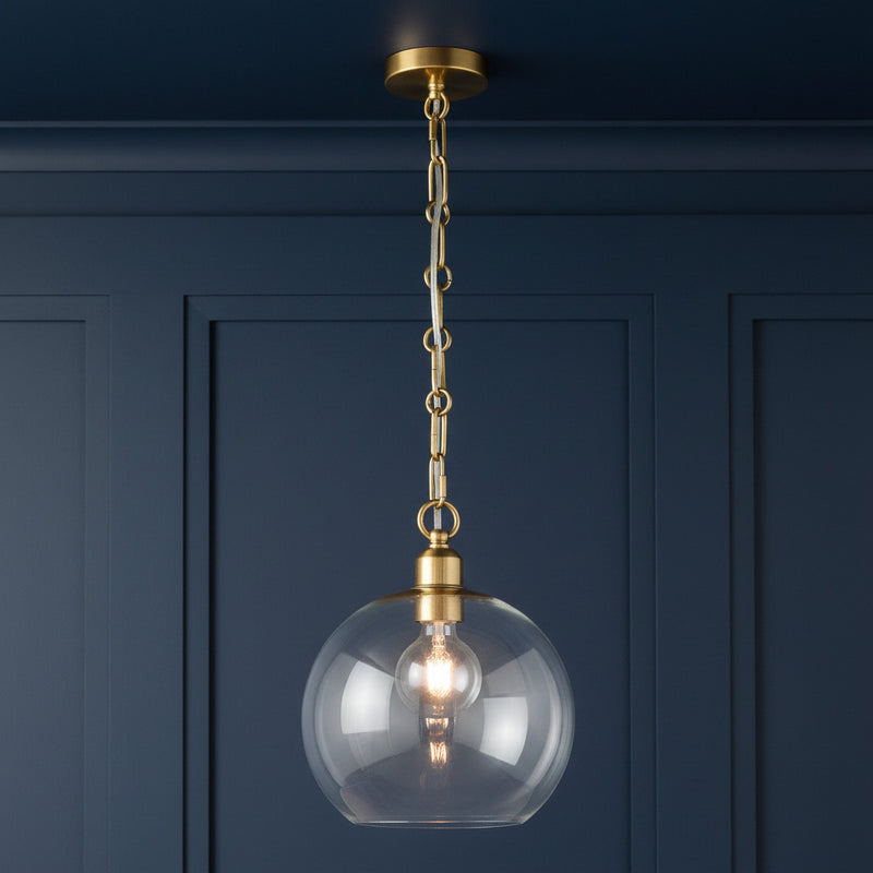 Clear glass pendant light with decorative gilt brass chain hanging from ceiling