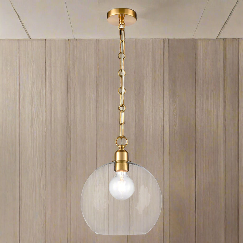 Clear glass pendant light with decorative gilt brass chain hanging from ceiling