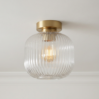 A modern semi-flush mount ceiling light featuring a ribbed clear glass shade and a brushed brass  ceiling rose