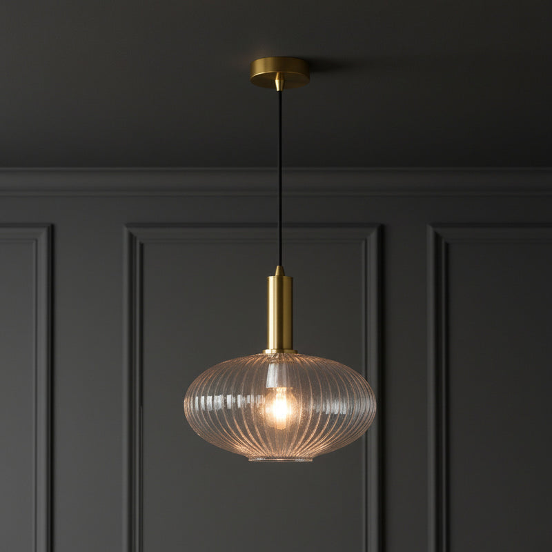 Pendant light with gold fixture and ribbed glass shade on a white background