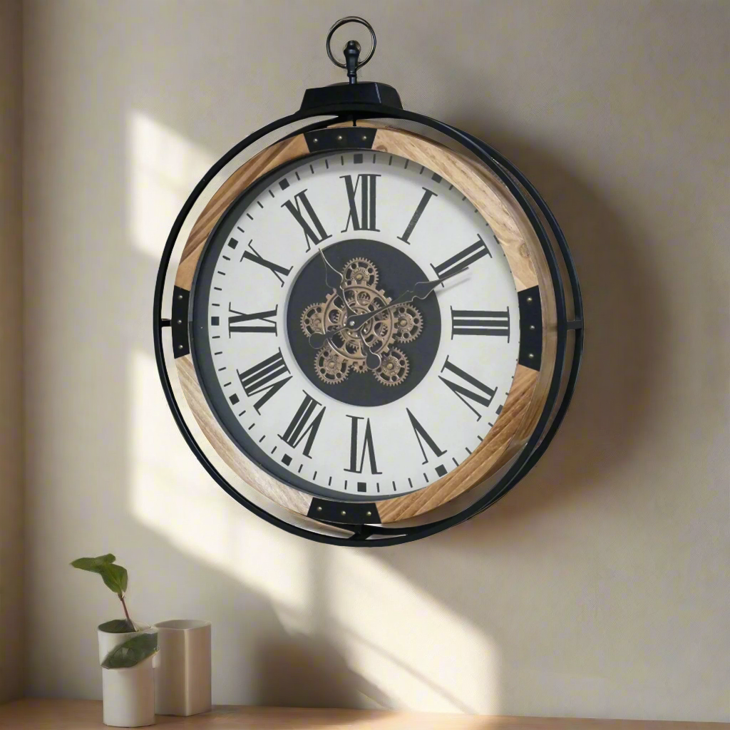 A wall clock with a black metal and wooden rim, featuring an antiqued cream face and moving cogs in the center, displayed on a wall.