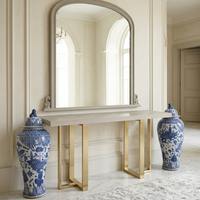 Decorative table with mirror and blue and white vases in a room with light-colored walls and floor.