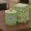 Handcrafted green ceramic scented candle jar with gold detailing and floral pattern, scented with warm amber, florals, and woods.