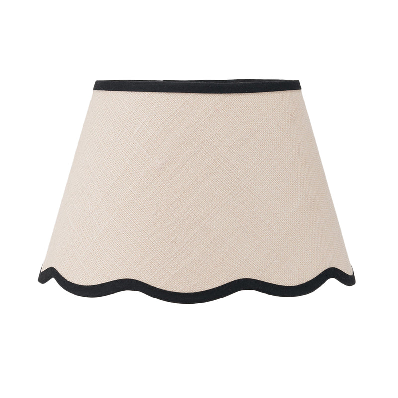 Cream tapered lampshade with scalloped bottom edge and contrasting black trim.