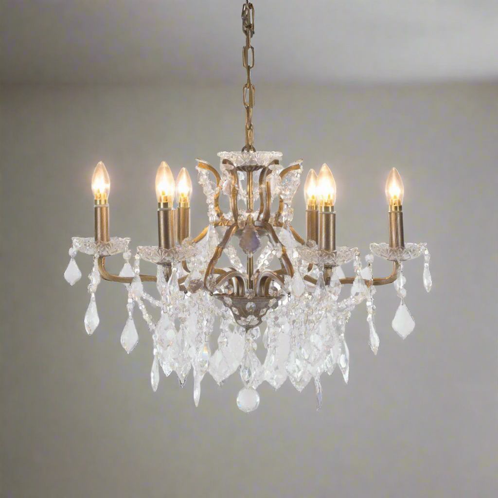 A beautiful six-arm crystal chandelier set on a warm gilt metal frame. With its shallow proportions and cascading crystal drops.