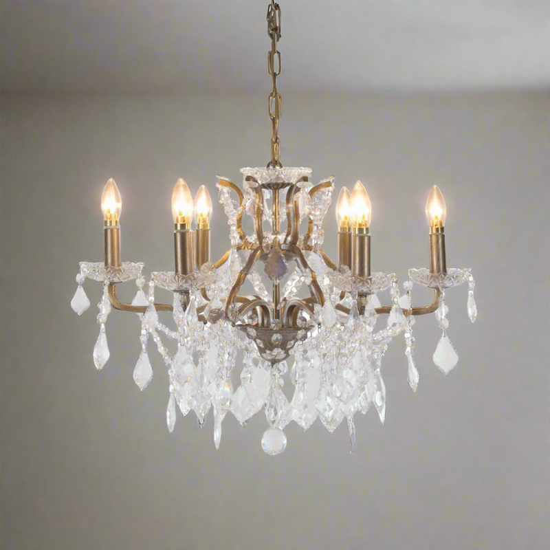 A beautiful six-arm crystal chandelier set on a warm gilt metal frame. With its shallow proportions and cascading crystal drops.