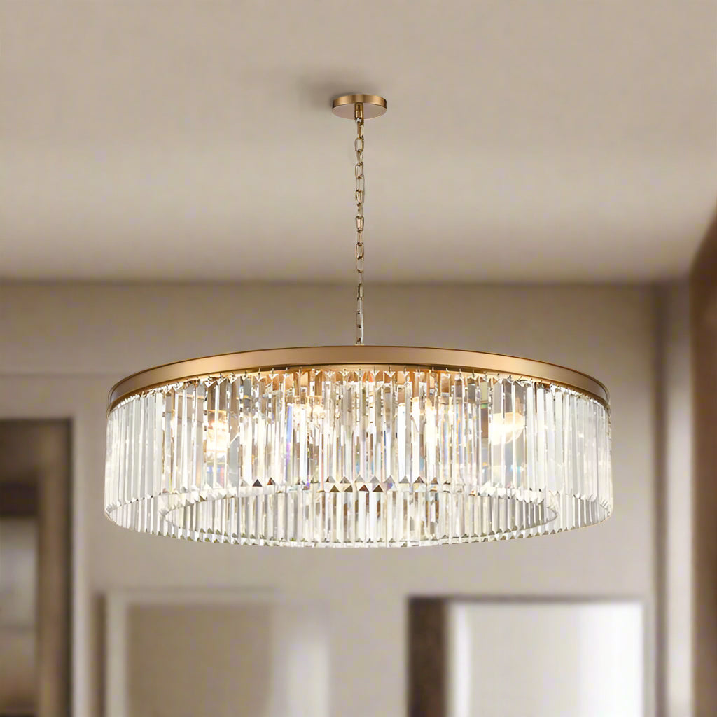 This chandelier pairs a smooth gold band with rows of shimmering prism-cut crystals, creating a striking, luxurious glow. With its impressive 100 cm width