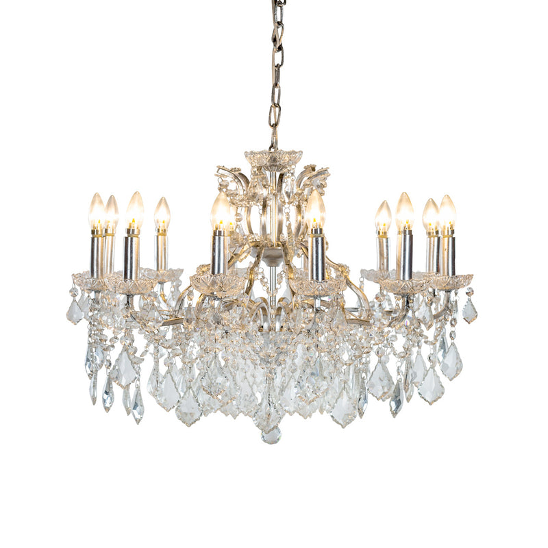This grand twelve-arm chandelier blends a silver frame with layers of sparkling crystals, creating a soft, romantic glow that brings elegance to any room.