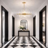 Luxurious hallway with a gold chandelier, black and white checkered floor, and decorative mirror.