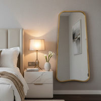 Curved gold metal mirror in a bedroom, 122cm high
