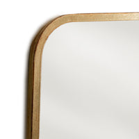 Close-up of the rounded corner and gold frame of the curved mirror