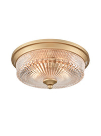 Gold flush mount ceiling light with ribbed glass dome and brass trim.