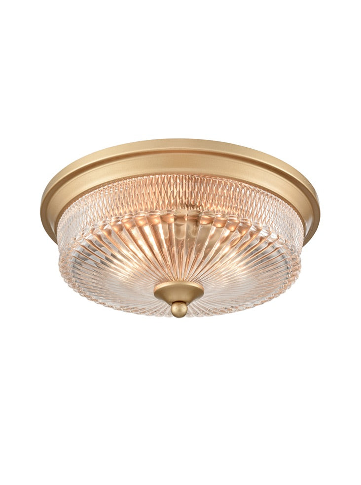 Gold flush mount ceiling light with ribbed glass dome and brass trim.