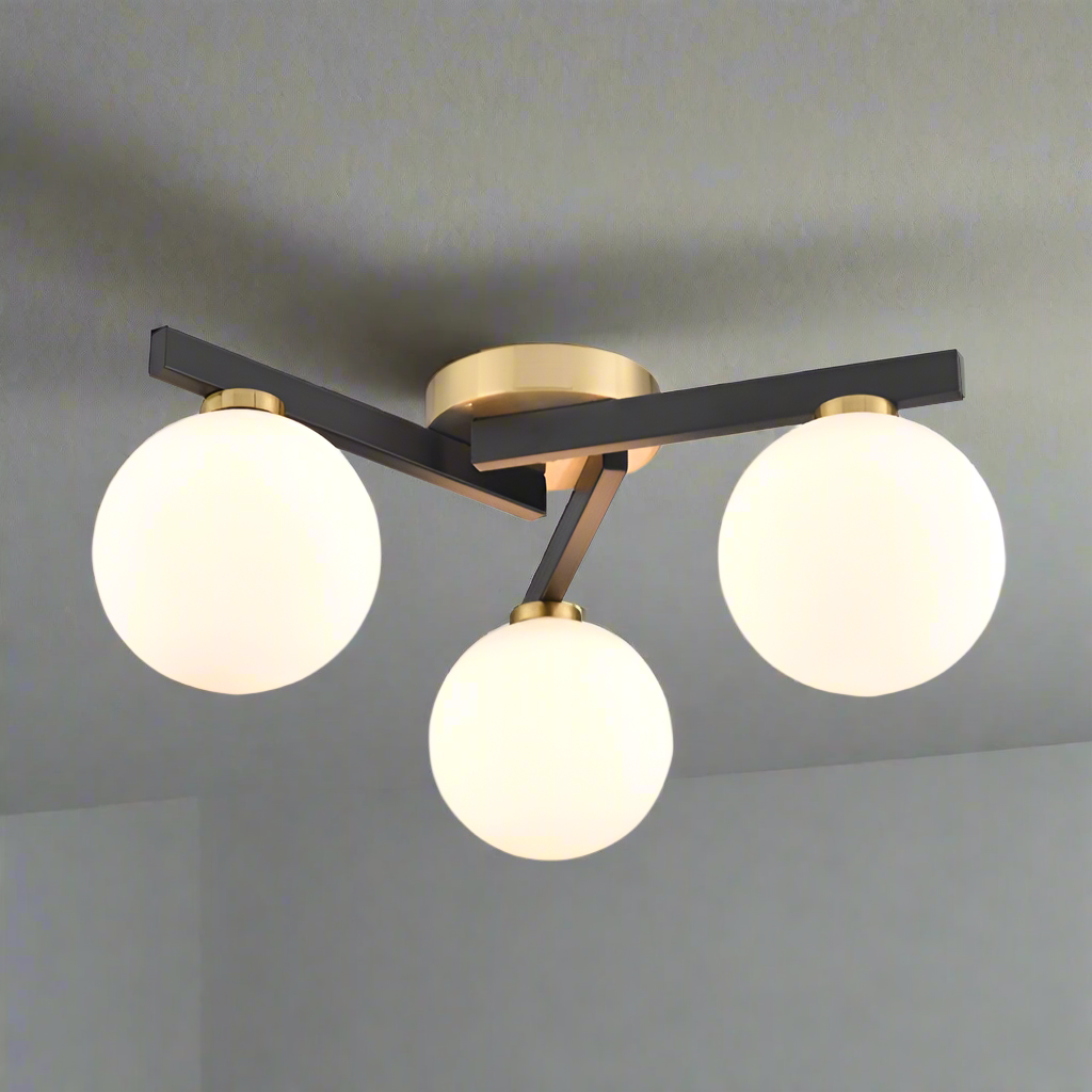 Modern low-profile flush mount ceiling light with three opal glass globe shades, matte black arms, and brushed brass accents in an asymmetric design.