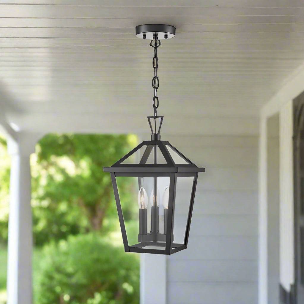 Black metal transitional-style hanging lantern with three candle-style bulbs enclosed in clear glass, suspended by a chain.