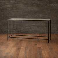 Long narrow table with black metal frame against a dark brick wall.