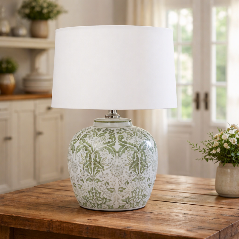 Decorative table lamp with a white shade on a wooden surface in a home setting.