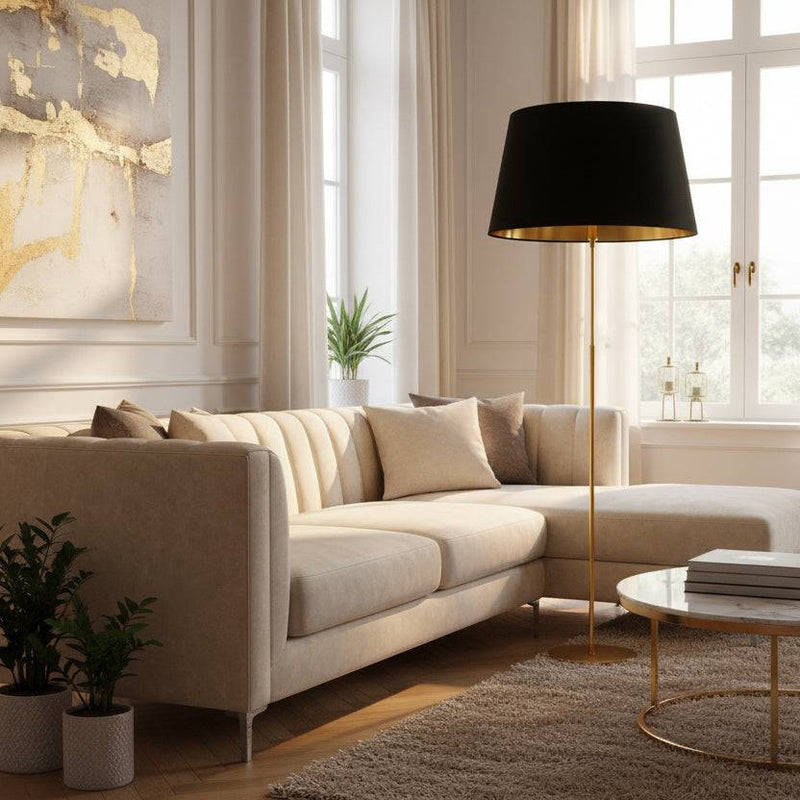 Oversized black velvet lampshade with gold lining on a gold floor lamp in a bright, elegant living room with cream sofa and large windows