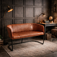 Brown leather sofa in a room with a textured wall and desk.
