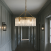 Elegant five‑light chandelier with vertical textured glass panels and a gilt metal frame, suspended by a chain in a hallway.