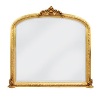 Ornate gilt overmantle mirror with a lavish gold leaf frame, decorative Rococo crest, and intricate baroque scrollwork .