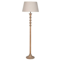 A floor lamp with a tall, slender distressed wood base and a tapered beige fabric drum shade, shown against a plain white background.