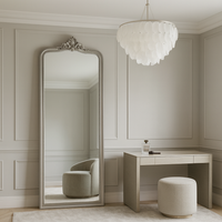 A tall, narrow silver framed mirror with decorative crown in a dressing room