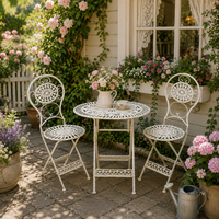 Three piece patio set under a cottage window in a cottage garden patio, with potted plants.