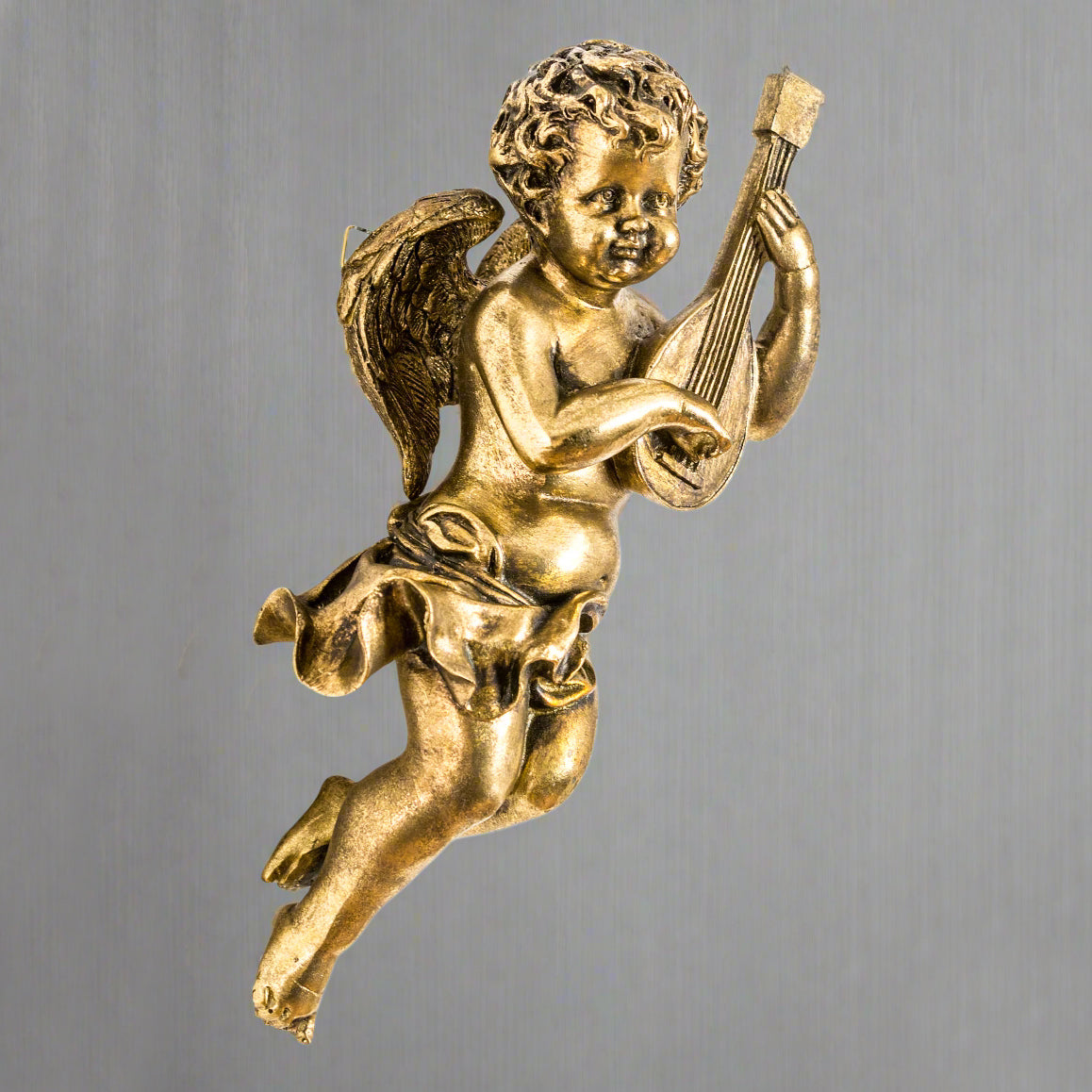Gold figure of a cherub playing a lyre on a grey background