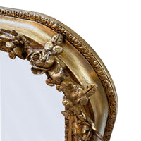 Close-up of an ornate gold mirror frame with intricate detailing on a white background