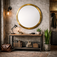 Round, banded gilt metal framed mirror,in an urban hall with industrial console table and limewashed walls.