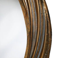 Detail of frame on a round wall mirror with a distressed gold, deeply textured frame. The swirling pattern of the frame adds a touch of elegance and movement to its design. The distressed gold finish gives a warm, antique feel. 