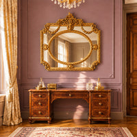 Heavily ornate gold panelled overmantle mirror with scrollwork, floral garlands, and oval center, reflecting a classic elegant interior