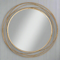 Circular mirror in gilt finish on a paneled grey wall.