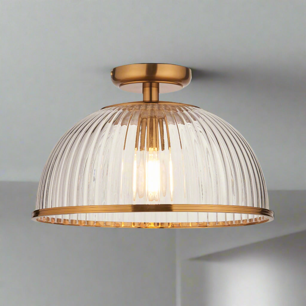 Illuminate your space with timeless elegance using this ribbed glass flush ceiling light with gilt metal detailing. Designed to combine classic sophistication with modern functionality, this semi-flush mount light fixture features a dome-shaped ribbed glass shade that diffuses light beautifully, creating a warm and inviting glow. The gilded metal frame and ceiling plate add a touch of luxury, making it a perfect statement piece for any interior.

This versatile ribbed glass ceiling light works effortlessly 