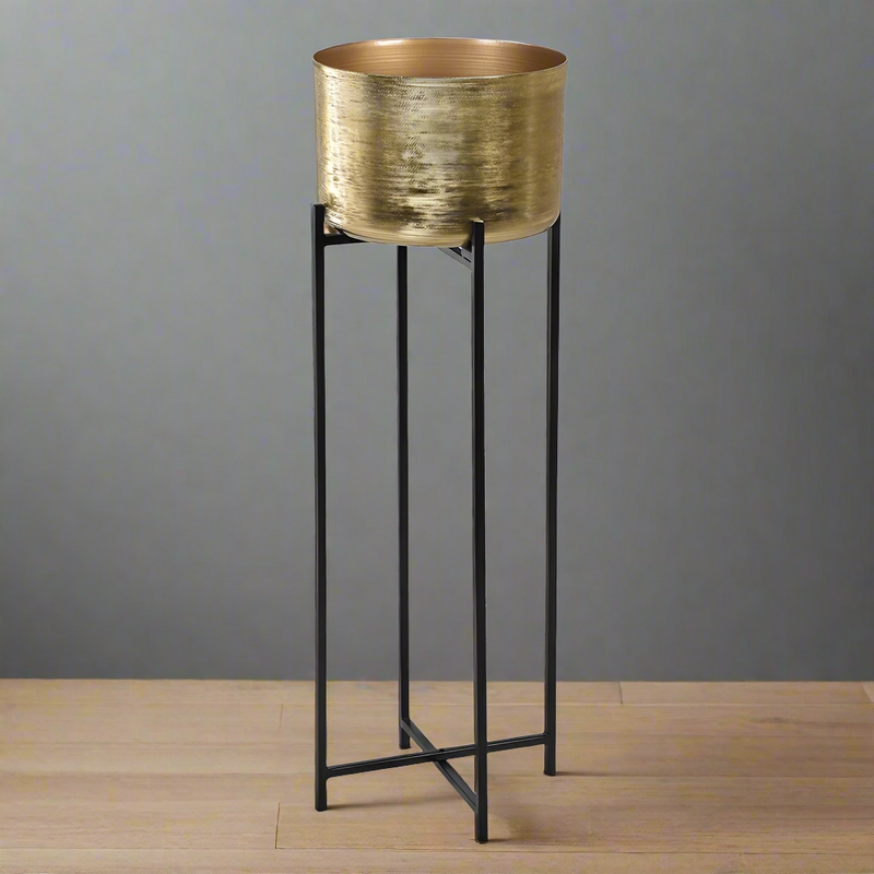 A very tall glamorous gold metal plant stand on tall slender black iron legs which will brighten and lift your patio or garden area. The gold metal plant pot is a useful 30cm diameter and the plant stand finishes at 94cm tall lending elegance and stature to any greenery, foliage or flowers you choose to plant in it. 