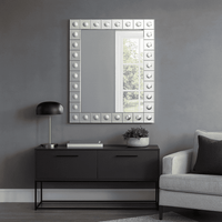 This is a Venetian-style wall mirror featuring a striking raised decorative frame. The rectangular mirror is bordered by a geometric design of square mirrored tiles, each accented with a raised circular dome detail that adds dimension, texture, and light-catching elegance. The reflective frame enhances the mirror’s brilliance, making it not only functional but also a bold decorative statement.

Its clean lines and sculptural frame give it a contemporary twist on classic Venetian design, making it versatile 