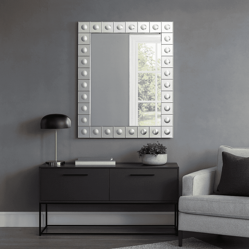This is a Venetian-style wall mirror featuring a striking raised decorative frame. The rectangular mirror is bordered by a geometric design of square mirrored tiles, each accented with a raised circular dome detail that adds dimension, texture, and light-catching elegance. The reflective frame enhances the mirror’s brilliance, making it not only functional but also a bold decorative statement.

Its clean lines and sculptural frame give it a contemporary twist on classic Venetian design, making it versatile 