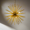 Small gold sunburst chandelier with brass metal rods forming a starburst shape, suspended from a chain.