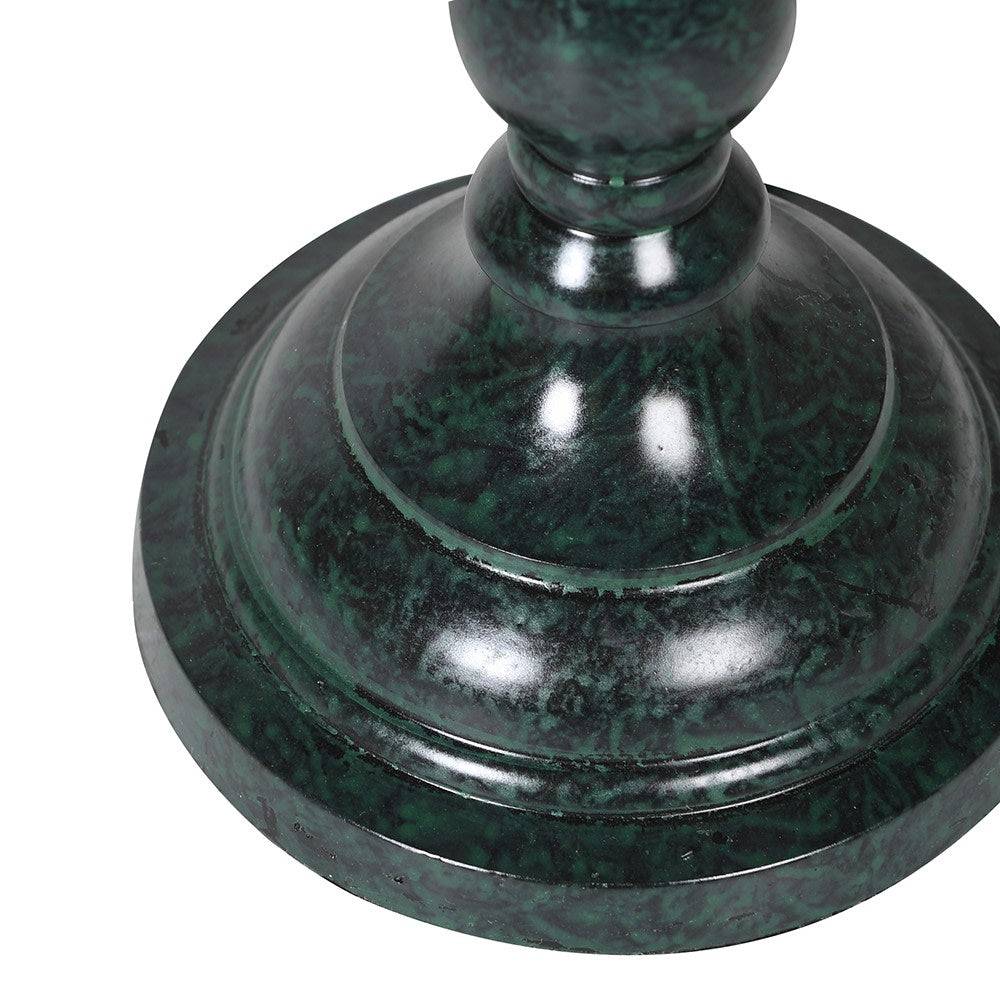 A slim very dark green, metal table lamp with a traditional design. It features a slender, ornate stand and a beige linen lampshade with a scalloped edge trimmed in blue. 
