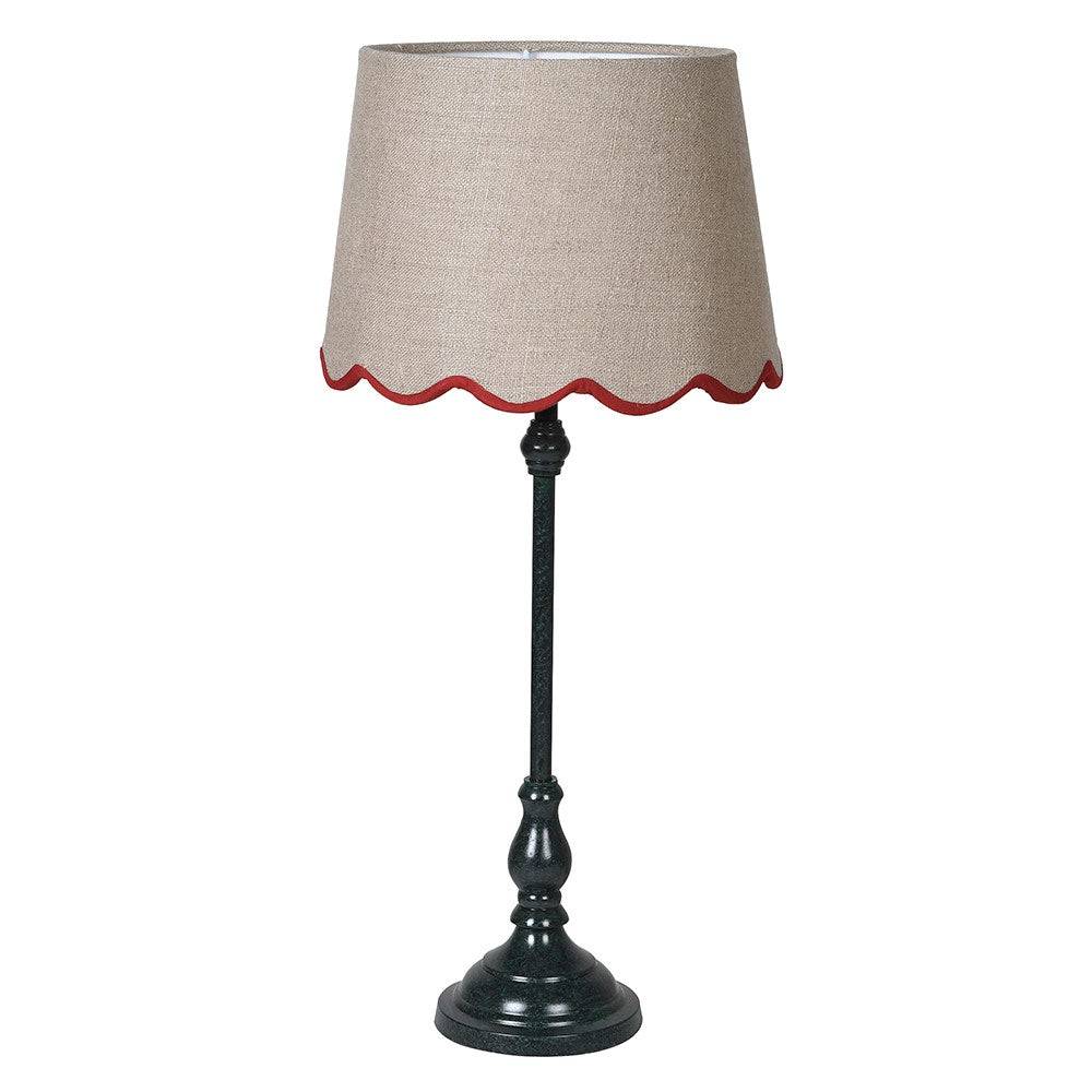 A slim dark green metal table lamp with a traditional design. It features a slender, ornate stand and a beige linen lampshade with a scalloped edge trimmed in red. 