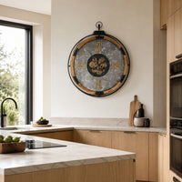 Large industrial wall clock with a grey marbled face, exposed moving cogs, Roman numerals, and a wooden inner frame in modern kitchen