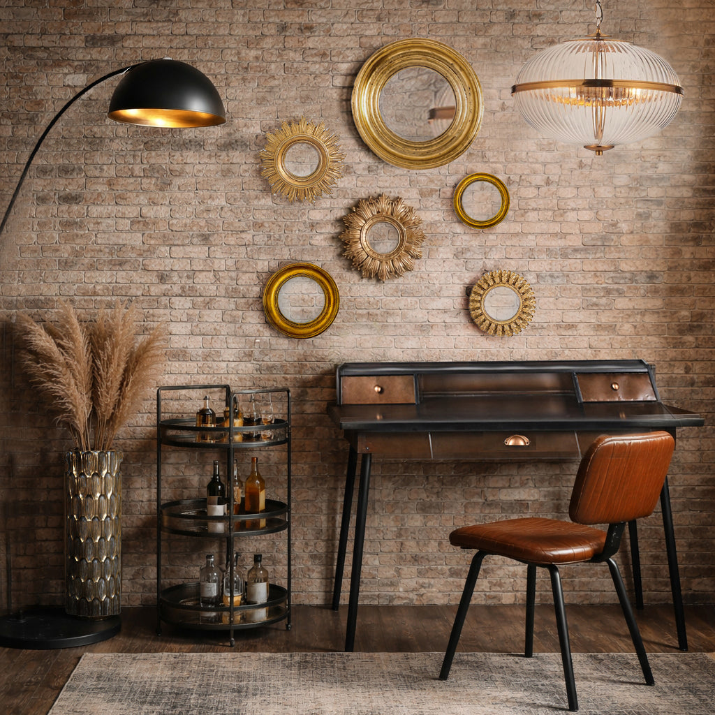 Decorative interior with a brick wall, round mirrors, a desk, and chair.